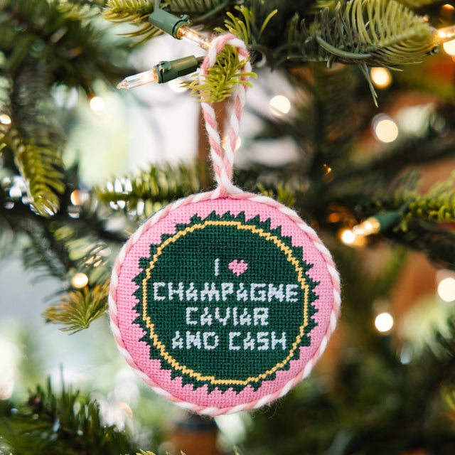 Decorative ornament with 'I love Champagne, caviar and cash' text on a Christmas tree.