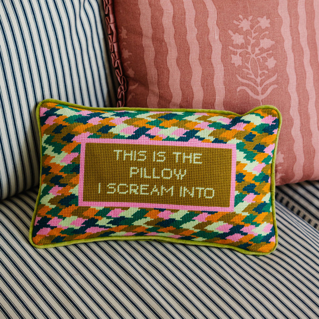 Decorative pillow with geometric pattern and text on a striped sofa