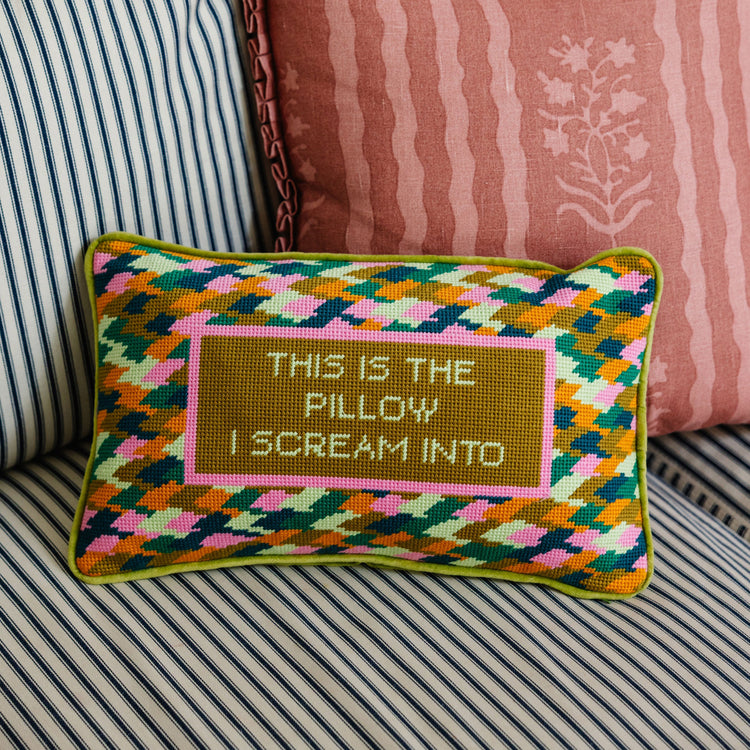 Decorative pillow with geometric pattern and text on a striped sofa