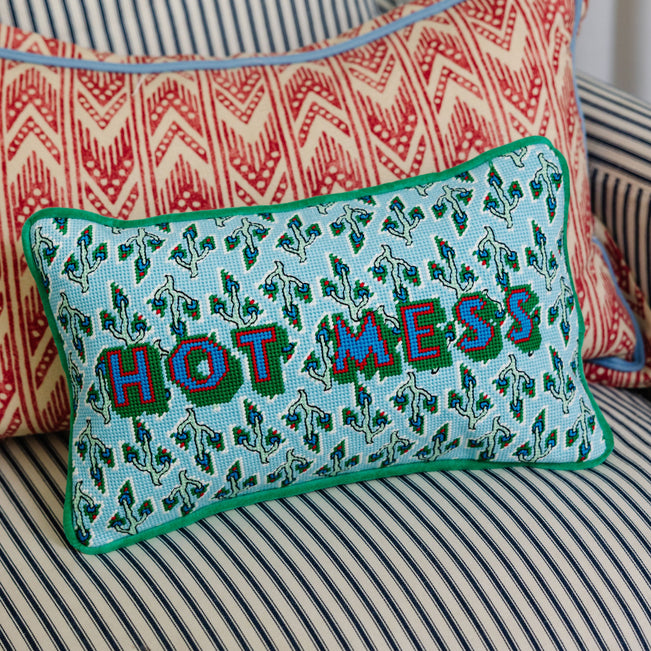 Decorative pillow with 'HOT MESS' text on a striped couch