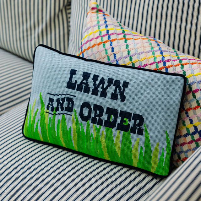 Decorative pillow with 'Lawn and Order' text on a striped sofa