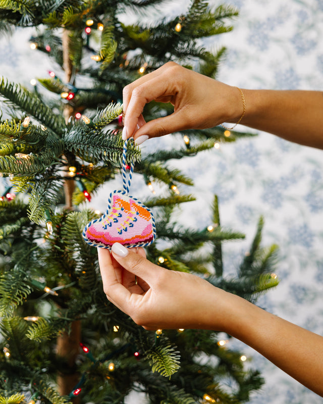 Person decorating a Christmas tree with a colorful ornament.