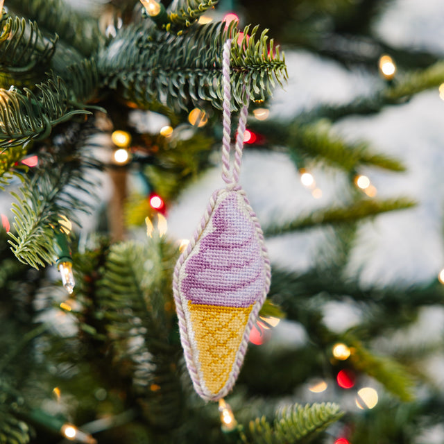 Decorative ice cream cone ornament on a Christmas tree with blurred lights in the background