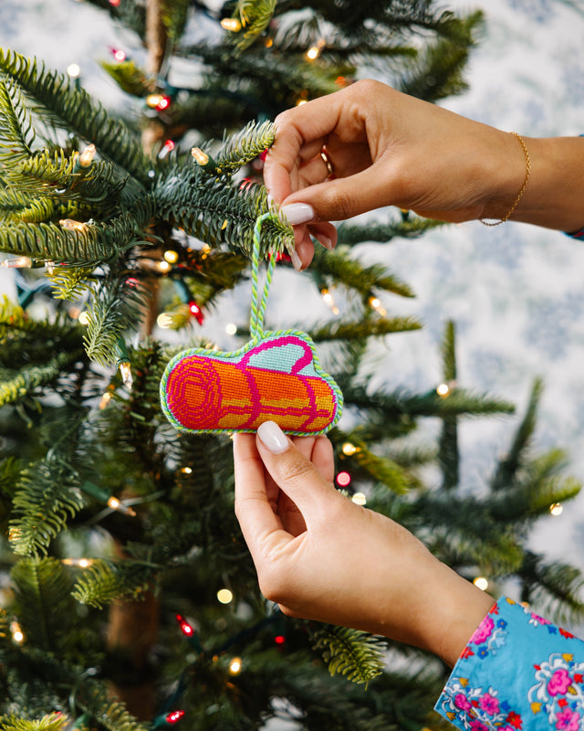 Person decorating a Christmas tree with a colorful ornament.