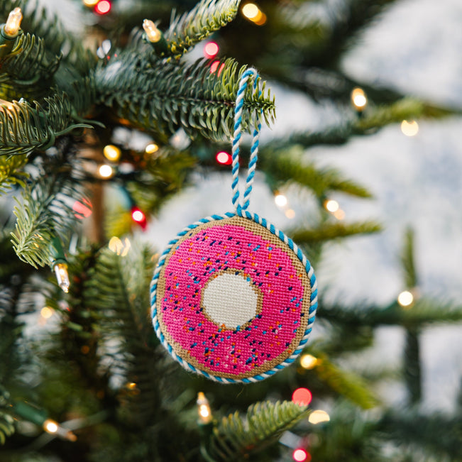 Decorative donut ornament on a Christmas tree with blurred lights in the background