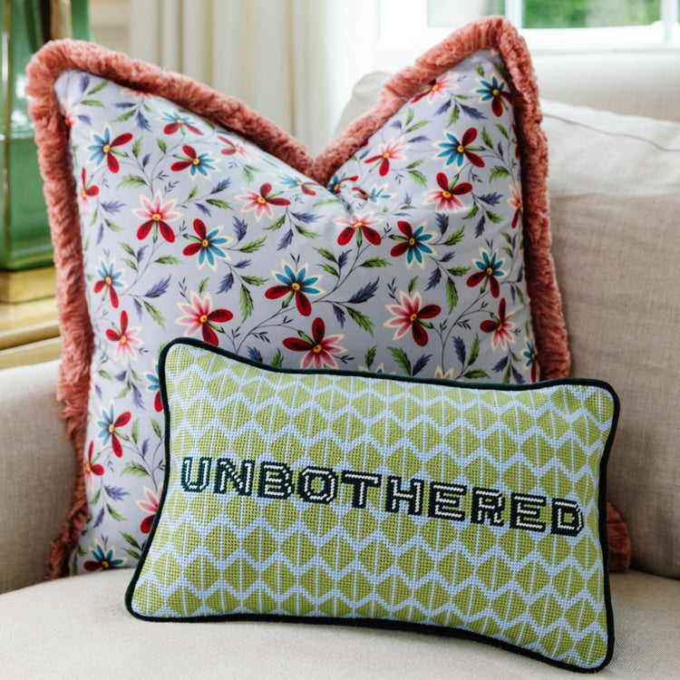 Decorative pillows with floral pattern and 'UNBOtherED' text on a couch.