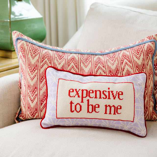 Decorative pillow with 'expensive to be me' text on a couch