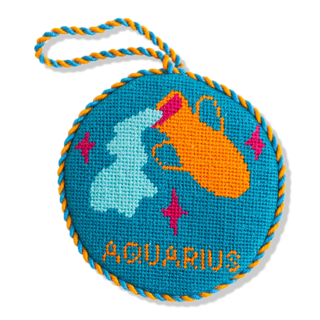 Round blue embroidered item with Aquarius design on a white background