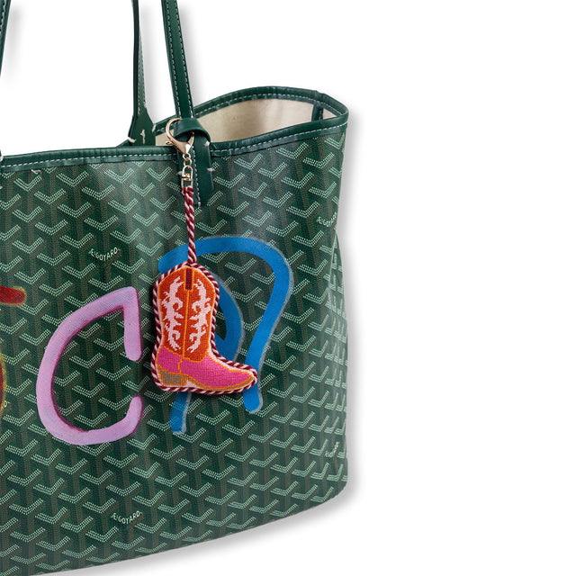 Green patterned handbag with a colorful keychain featuring a boot design on a white background