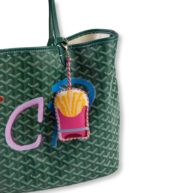 Green patterned handbag with a colorful keychain on a white background