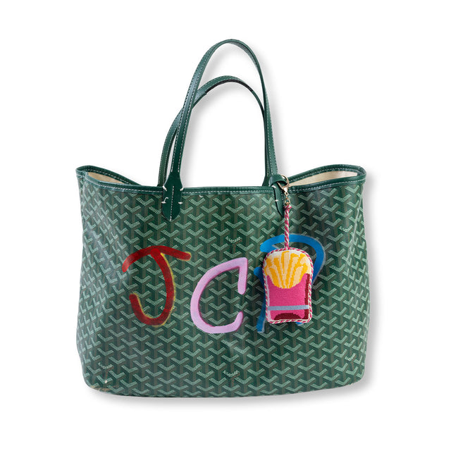 Green patterned tote bag with colorful 'JC' initials and a French fry charm on a white background