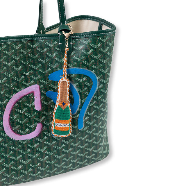Green patterned handbag with a colorful keychain attached on a white background