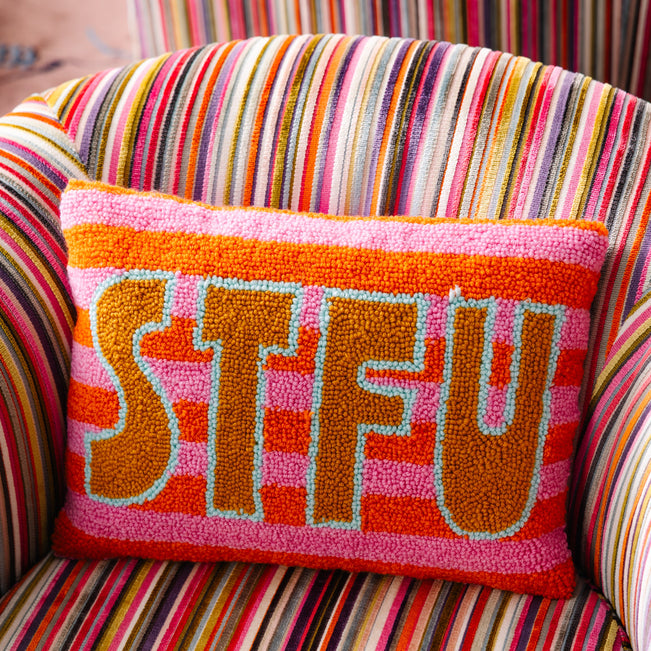Colorful pillow with 'STFU' text on a striped chair