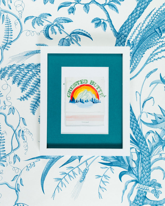 Crested Butte Matchbook - Furbish Studio, A matchbook watercolor print illustrating the Crested Butte Ski Resort's surroundings through a watercolor paint and it is below the dark green painted "Crested Butte" in a 5x7 white frame with a wallpaper background