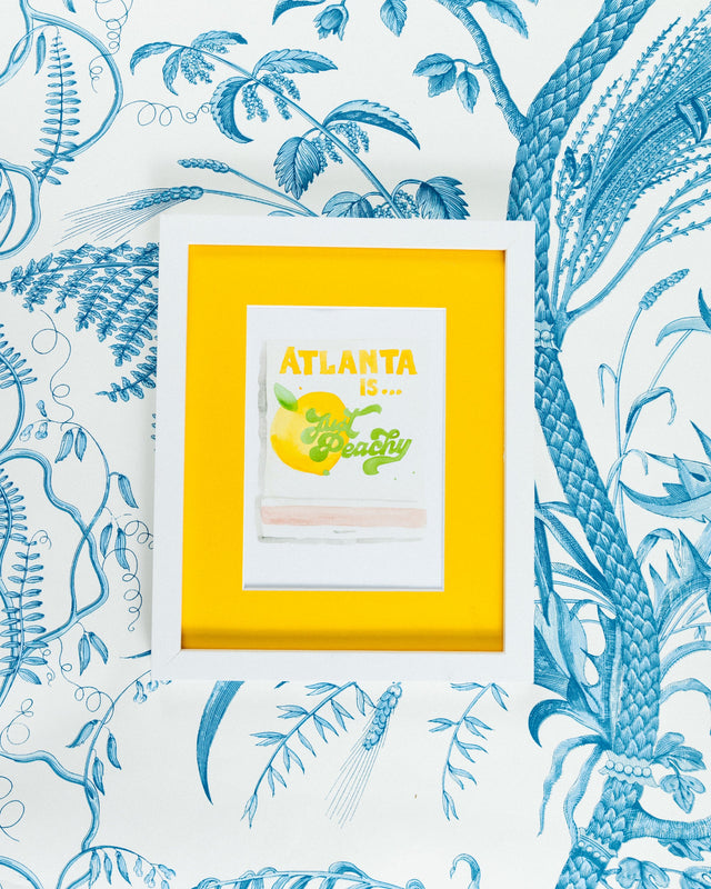 Atlanta Matchbook - Furbish Studio, Atlanta matchbook watercolor print with a yellow peach fruit paint under the saying "Atlanta is... Just Peachy" in a 5x7 white frame with a wallpaper background